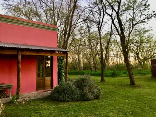 a red house with a bench in a yard at Casa de Campo La Colorada in Las Flores