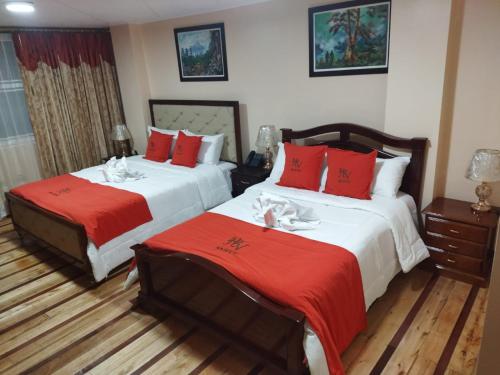 duas camas num quarto de hotel com almofadas vermelhas em HOTEL VELANEZ SUITE Riobamba em Riobamba