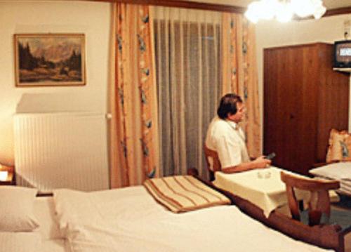 a man standing in a bedroom with two beds at Gasthof Karlwirt in Sankt Andrä im Lungau