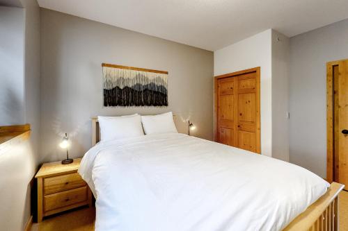 a bedroom with a large white bed and a wooden cabinet at Bears Paw 5 in Big White
