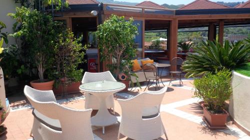 a patio with white chairs and tables and plants at Hotel Residence Piccolo in Parghelia
