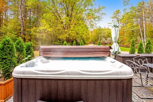 a hot tub in a backyard with an umbrella at 6 Bedroom House at Schroon River in Brant Lake