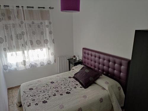 a bed with a purple headboard in a bedroom at Casa El Callejo de La Fregeneda in La Fregeneda