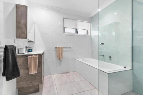 a bathroom with a shower and a tub and a sink at Bribie Island Canal Holiday Destination! in Bongaree