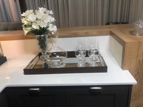 a tray with three wine glasses and a vase with flowers at Espetacular sítio com belíssima paisagem para descansar in Cobras