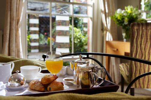 a table with a tray of breakfast food and orange juice at Lainston House in Winchester