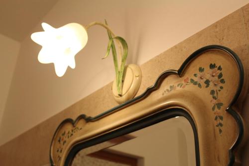 a mirror with a plant on the wall next to a light at B&B Acero Rosso in San Giovanni Lupatoto