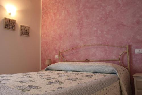 a bedroom with a bed with a pink wall at B&B Acero Rosso in San Giovanni Lupatoto