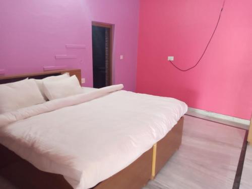 a bedroom with a bed with a pink wall at CHÉRI HOME Stay in Khajurāho