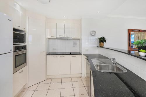 a kitchen with white cabinets and a sink at Rovera Apartments in Maroochydore