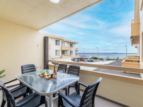 a table and chairs on a balcony with a view of the ocean at 4 Bay Village 51 Shoal Bay Rd in Shoal Bay