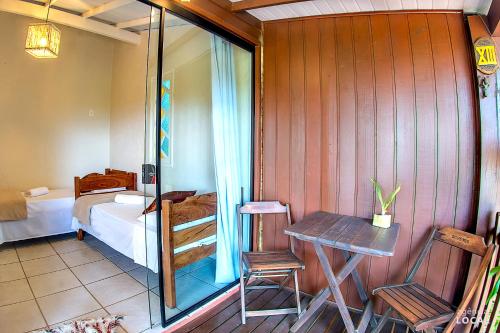 a room with a bedroom with a bed and a table at Pousada Rosa in Praia do Rosa