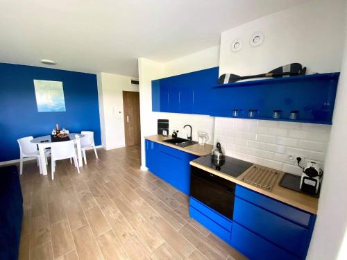uma cozinha com armários azuis e uma mesa com cadeiras em Apartamenty Pod Żaglami em Zegrze
