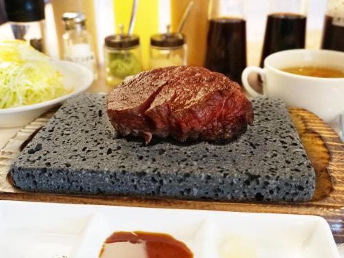 a piece of meat on a cutting board with a cup of coffee at Hotel Abest Osu Kannon Ekimae Hane no Yu in Nagoya