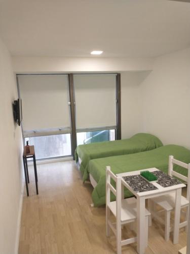 Cette chambre comprend 4 lits verts et une table. dans l'établissement Verde Esmeralda, à Buenos Aires