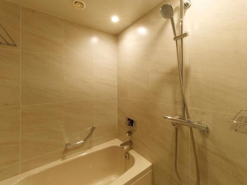 a bathroom with a shower with a tub and a bath tub at Hotel Keihan Tsukiji Ginza Grande in Tokyo