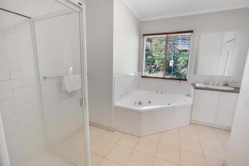 a white bathroom with a tub and a shower at Lakes Edge in Lakes Entrance