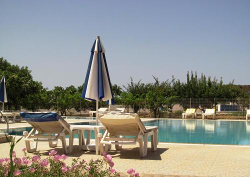 a table with two chairs and an umbrella next to a pool at Paraschos Studios Kos in Kardamaina