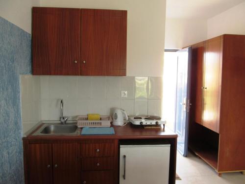 a kitchen with wooden cabinets and a sink at Paraschos Studios Kos in Kardamaina