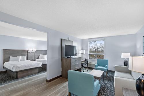Habitación de hotel con cama y TV en Emerald Hotel & Suites Calgary Airport en Calgary