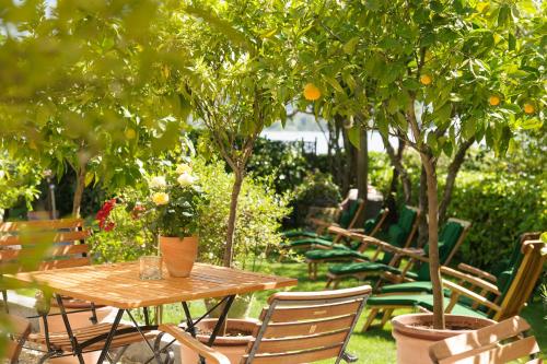 a wooden table and chairs with orange trees in a garden at Hotel Barleben am See in Konstanz