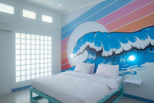 a bedroom with a painting of a wave at Mad Monkey Kuta Lombok in Kuta Lombok
