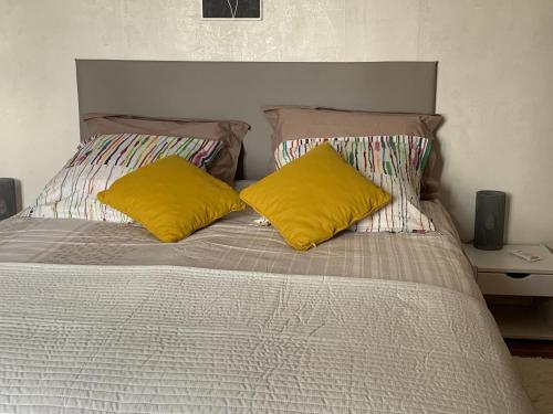 Una cama con dos almohadas amarillas encima. en Fontanies en Aubrac en Laguiole