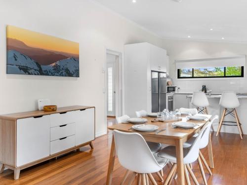 a kitchen and dining room with a wooden table and white chairs at Jillamatong 14 - 3BR House l Pet Friendly l Fenced Backyard l WiFi in Jindabyne