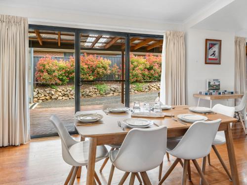 a dining room with a wooden table and white chairs at Jillamatong 14 - 3BR House l Pet Friendly l Fenced Backyard l WiFi in Jindabyne