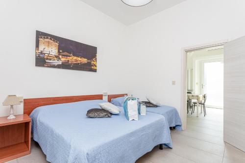 una camera con due letti con lenzuola blu e una finestra di Nicola House "Torre San Michele" a Cervia