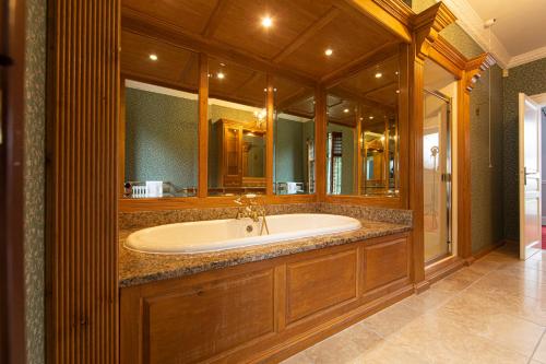 uma grande casa de banho com uma banheira e um espelho grande em Swansea Valley Holiday Cottages em Cilybebyll