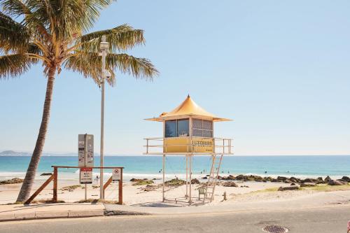 a lifeguard tower on the beach with a palm tree at X Kirra Apartments in Gold Coast