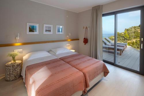 a bedroom with a large bed and a balcony at Kechria Bay Villas in Skiathos