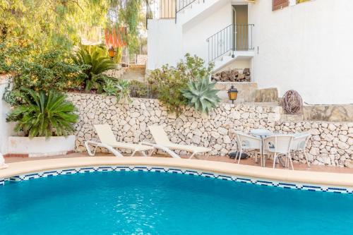 a pool with chairs and a table next to a building at El Refugio - Quite and Spacious in Benissa