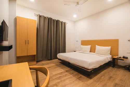 a bedroom with a bed and a desk and a tv at FabHotel Kingston House in Lucknow