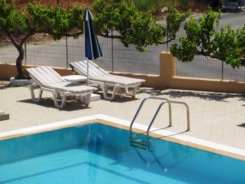 a swimming pool with two chairs and an umbrella at Paraschos Studios Kos in Kardamaina