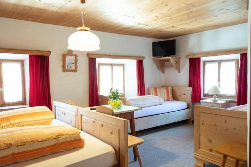 a bedroom with two beds and red curtains at Alpina B&B Apartments in Santa Maria Val Müstair