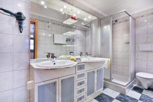 a bathroom with two sinks and a shower and a toilet at Gästehaus Oslhof Ferienwohnungen in Ramsau