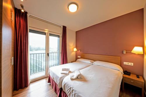a hotel room with a bed and a large window at Aparthotel Trainera in Esterri d'Àneu