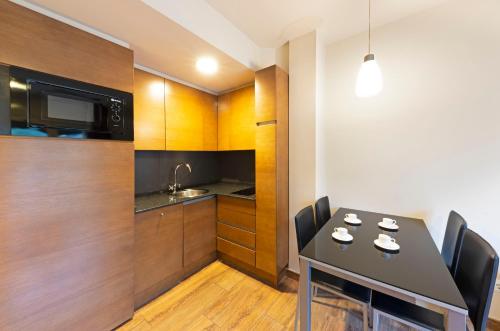 a kitchen with a black table with chairs and a microwave at Aparthotel Trainera in Esterri d'Àneu