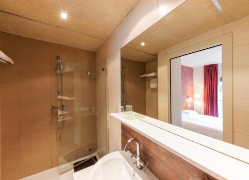 a bathroom with a shower and a sink and a mirror at Aparthotel Trainera in Esterri d'Àneu