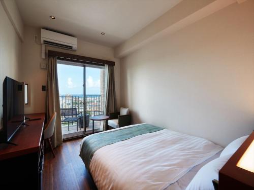 a hotel room with a bed and a desk and a window at THE GRAND HOTEL GINOWAN in Ginowan