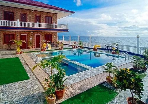 une maison avec une piscine à côté de l'océan dans l'établissement RedDoorz Plus Billy's Resort Oslob, à Oslob