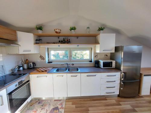 a kitchen with white cabinets and a stainless steel refrigerator at Rooms and Apartments IstraSoley in Bale