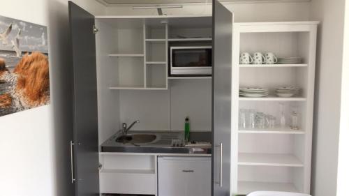 eine Küche mit einer Spüle und einer Mikrowelle in der Unterkunft Bungalow im Erlengrund in Rostock