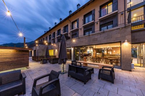 a hotel patio with chairs and tables and an umbrella at Aparthotel Trainera in Esterri d'Àneu