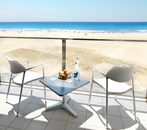 a table and chairs with a bowl of fruit on the beach at Bel Air in Castelldefels