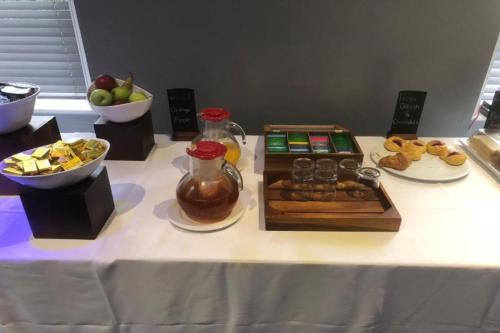 a table with a buffet of pastries and a bowl of fruit at Broadfield Park Hotel in Rochdale