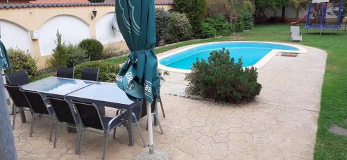 a table and chairs next to a swimming pool at Kenguru Panzió és Csárda in Hódmezővásárhely