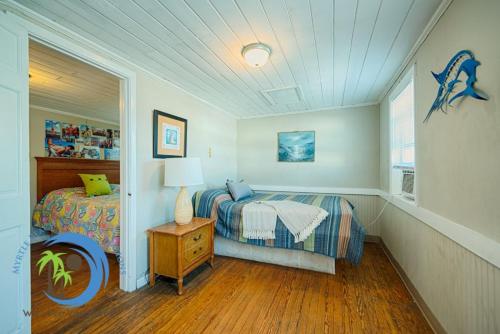 a bedroom with a bed and a table with a lamp at Oceanfront Ocean Drive Cottage in Myrtle Beach